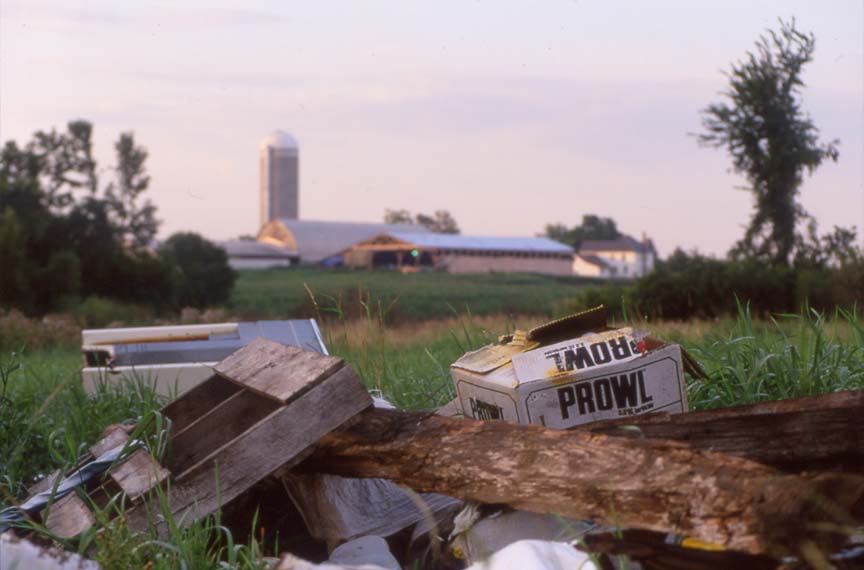 piled trash for burning with dairy farm in background